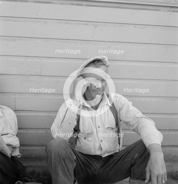 Bindle stiff, used to be logger, Side of Pastime Café, Tulelake, Siskiyou County, California, 1939. Creator: Dorothea Lange.