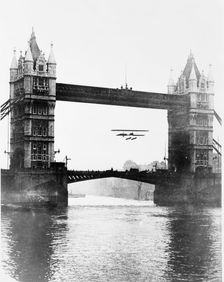 Biplane flying under Tower Bridge, Stepney, Tower Hamlets, London. Creator: Unknown
