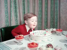 Birthday boy blowing out the candles on his cake, c1955. Creator: Arthur Charles Kirby Ware