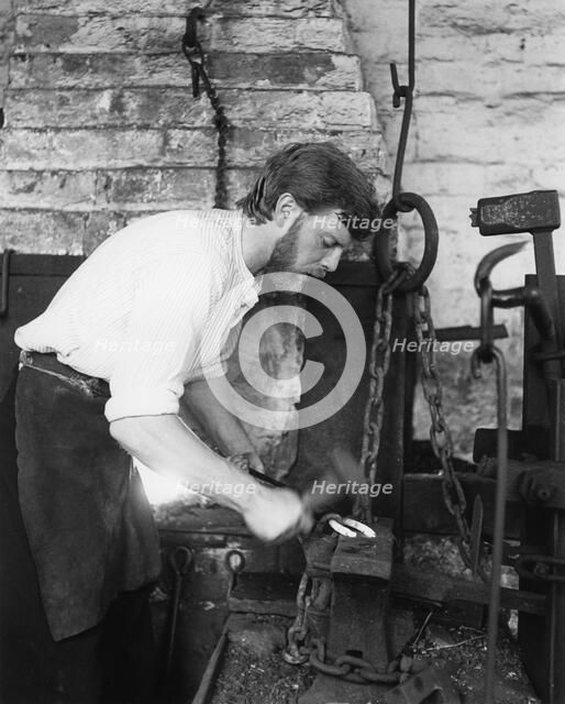 Black Country Museum, Birmingham, West Midlands, 1986. A blacksmith at work in a smithy.
