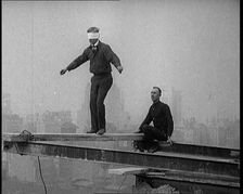 Blindfolded Man Walking Across a Plank Suspended from Iron Girders High Above the City Streets, 1921 Creator: British Pathe Ltd