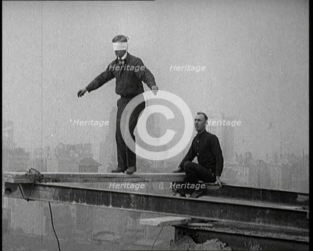 Blindfolded Man Walking Across a Plank Suspended from Iron Girders High Above the City Streets, 1921 Creator: British Pathe Ltd.