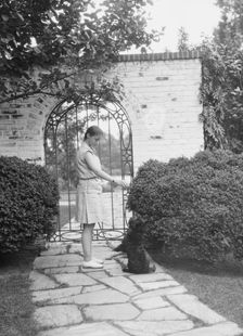 Brady, Genevieve, Miss, with dog, standing outdoors, between 1928 and 1931. Creator: Arnold Genthe