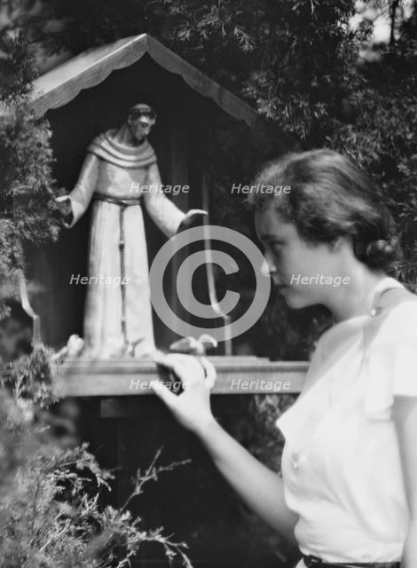Brady, Victoria, Miss, with a statue of St. Francis in a garden, 1931 July 14. Creator: Arnold Genthe.