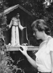 Brady, Victoria, Miss, with a statue of St. Francis in a garden, 1931 July 14. Creator: Arnold Genthe