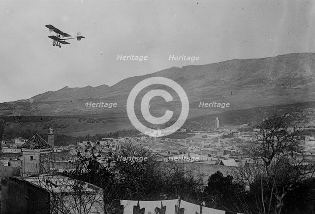 Breguet biplane, type 1910, flying over a town, possibly in Morocco, between c1910 and c1915. Creator: Bain News Service.