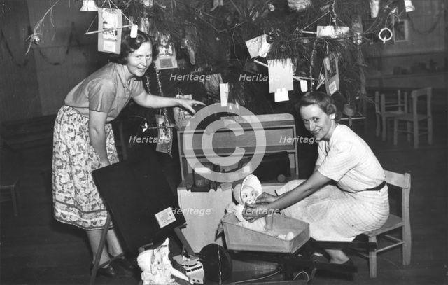Brisbane Kindergarten Teachers College students/staff with presents and the Christmas tree, 1955. Creator: Unknown.