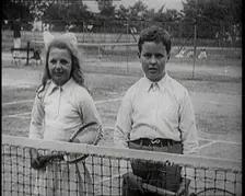 British Tennis Player Betty Nuttall as a Child, Standing on a Tennis Court With a Young Boy, 1921. Creator: British Pathe Ltd