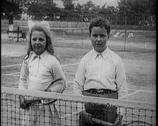 British Tennis Player Betty Nuttall as a Child, Standing on a Tennis Court With a Young Boy, 1921. Creator: British Pathe Ltd