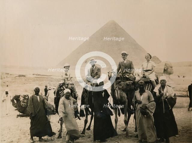 British tourists seated on camels in front of The Great Pyramid, Giza, Egypt, 1936. Artist: Unknown