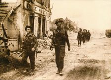 British troops walk through the village of Douet, after the fall of Bayeux, June 1944