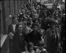 British Women and Child Evacuees Walking Along the Pavement of a Residential Street Next..., 1939. Creator: British Pathe Ltd