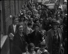 British Women and Child Evacuees Walking Along the Pavement of a Residential Street Next..., 1939. Creator: British Pathe Ltd