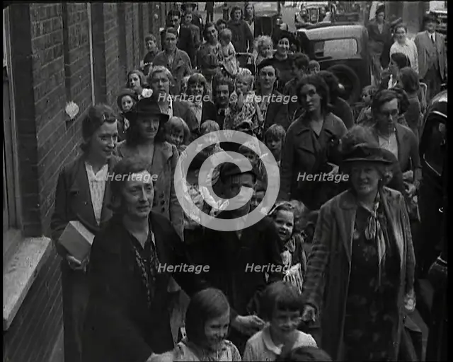 British Women and Child Evacuees Walking Along the Pavement of a Residential Street Next..., 1939. Creator: British Pathe Ltd.