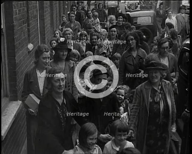 British Women and Child Evacuees Walking Along the Pavement of a Residential Street Next..., 1939. Creator: British Pathe Ltd.