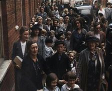 British Women and Child Evacuees Walking Along the Pavement of a Residential Street Next..., 1939. Creator: British Pathe Ltd