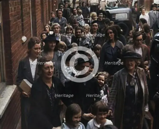 British Women and Child Evacuees Walking Along the Pavement of a Residential Street Next..., 1939. Creator: British Pathe Ltd.