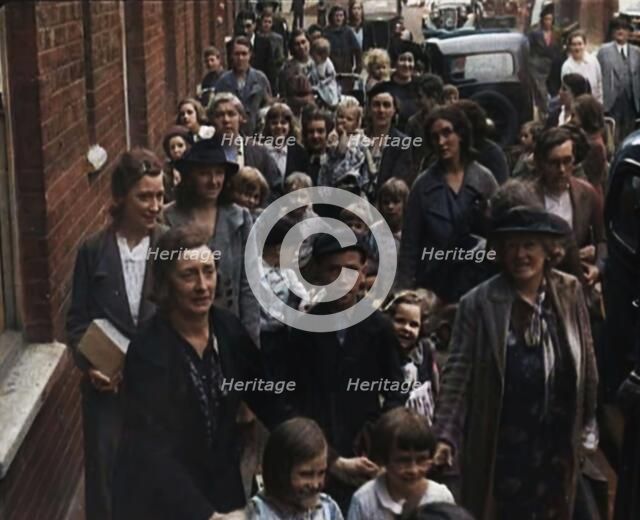 British Women and Child Evacuees Walking Along the Pavement of a Residential Street Next..., 1939. Creator: British Pathe Ltd.