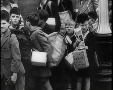 British Child Evacuees Standing on a Pavement With Bags and Boxes as Adults are Standing..., 1939. Creator: British Pathe Ltd
