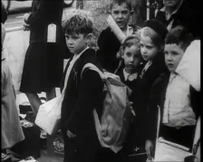 British Child Evacuees Standing on a Pavement With Bags and Boxes as Adults are Standing..., 1939. Creator: British Pathe Ltd