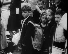 British Child Evacuees Standing on a Pavement With Bags and Boxes as Adults are Standing..., 1939. Creator: British Pathe Ltd