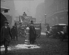 British Civilians Going About their Daily Commute on a Snowy Day on the Streets Watched by..., 1920. Creator: British Pathe Ltd