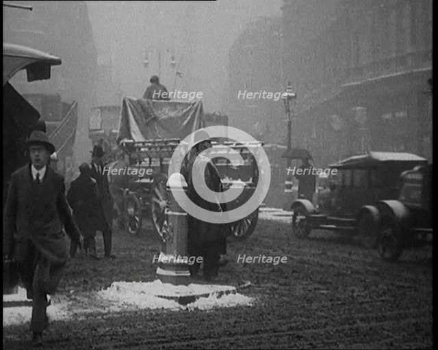 British Civilians Going About their Daily Commute on a Snowy Day on the Streets Watched by..., 1920. Creator: British Pathe Ltd.