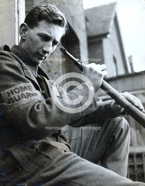 British Home Guard soldier cleaning his rifle, World War II, c1940-c1944. Artist: Unknown