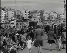 British Holidaymakers Walking Along the Promenade or Sitting on Deckchairs at Brighton..., 1938. Creator: British Pathe Ltd