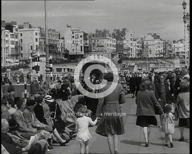 British Holidaymakers Walking Along the Promenade or Sitting on Deckchairs at Brighton..., 1938. Creator: British Pathe Ltd.