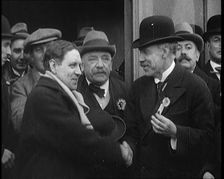 British Man Exiting a Building and Shaking Hands as Part of a by Election Campaign, 1921. Creator: British Pathe Ltd