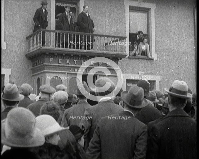 British Man Speaking to a Crowd from the Balcony of a Building Marked 'Feathers J. Davies..., 1921. Creator: British Pathe Ltd.