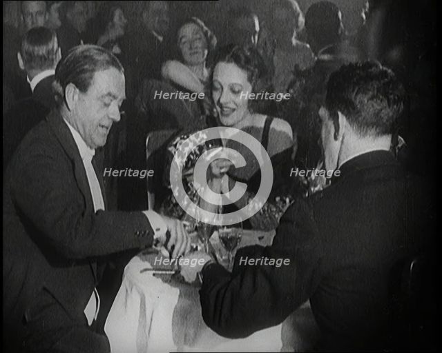 British Men and Women Sitting and Talking and Smoking at a Table in a Nightclub, 1922. Creator: British Pathe Ltd.