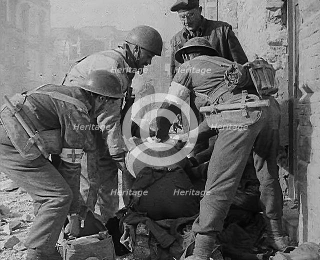 British Medics Helping a Fellow Soldier, 1943-1944. Creator: British Pathe Ltd.