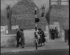 British People Walking by Heavily Sandbagged Buildings, 1940. Creator: British Pathe Ltd