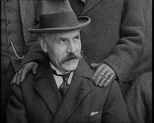British Prime Minister Ramsay MacDonald Sitting Down. a Pair of Hands Rests on His Shoulders, 1924. Creator: British Pathe Ltd