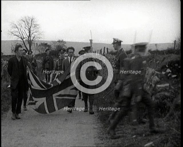 British Soldiers Marching a Sinn Fein Supporter Down a Country Lane, Forcing Him to Bear..., 1920. Creator: British Pathe Ltd.