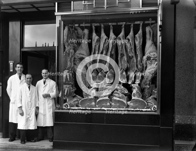 Butchers standing next to their shop window display, South Yorkshire, 1955.  Artist: Michael Walters