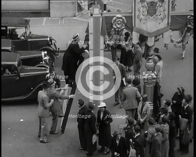 Bud Flanagan With a Frying Pan Climbing a Ladder Resting Against Coronation Decorations in..., 1937. Creator: British Pathe Ltd.