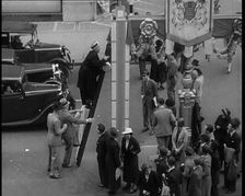 Bud Flanagan With a Frying Pan Climbing a Ladder Resting Against Coronation Decorations in..., 1937. Creator: British Pathe Ltd