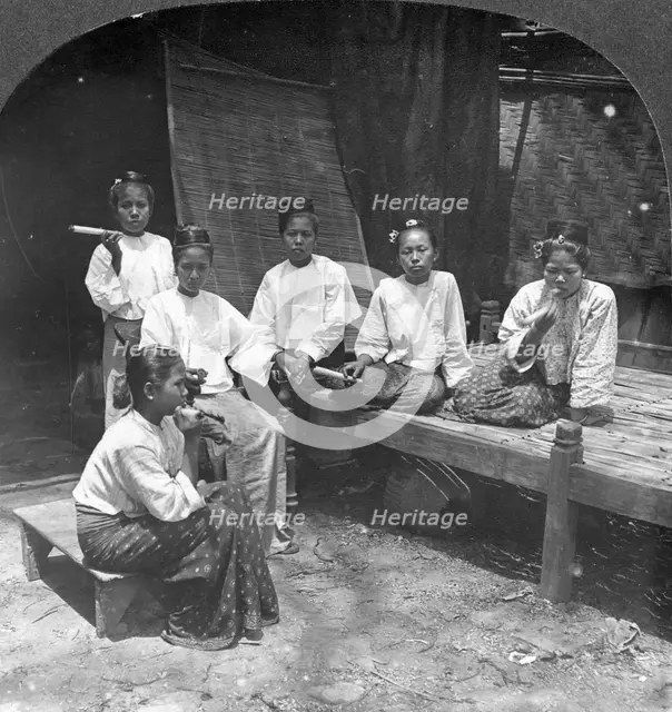Burmese women smoking outside their home, Mandalay, Burma, 1908.  Artist: Stereo Travel Co