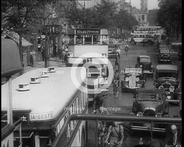 Buses, Cars and People on Bikes Driving Down the Road, 1933. Creator: British Pathe Ltd.