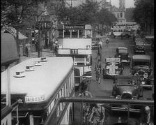Buses, Cars and People on Bikes Driving Down the Road, 1933. Creator: British Pathe Ltd