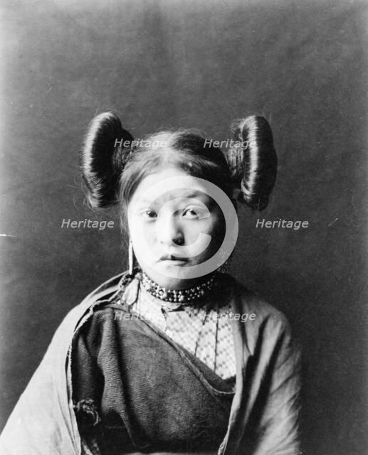 Gobuguoy, Walpi girl, half-length portrait, facing front, hair tied in swirls on sides of..., c1900. Creator: Edward Sheriff Curtis.