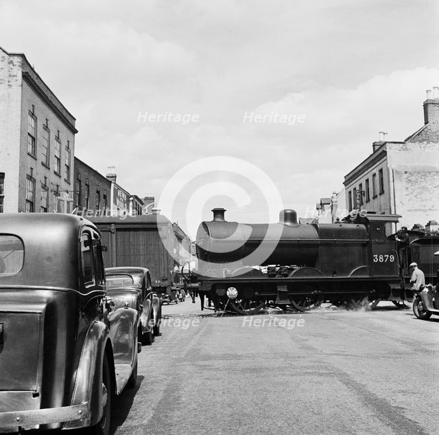 Goods vehicles being shunted across the un-gated level crossing in High Street, Tewkesbury, 1947. Creator: Marjory L Wight.