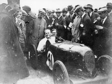 Gordon Taylor in a racing car surrounded by a crowd of men