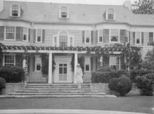 Gossler, Philip, Mrs., standing in front of residence, between 1927 and 1929. Creator: Arnold Genthe