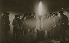 Gathering around an acetylene flare at a traffic control point in the fog, early 20th century
