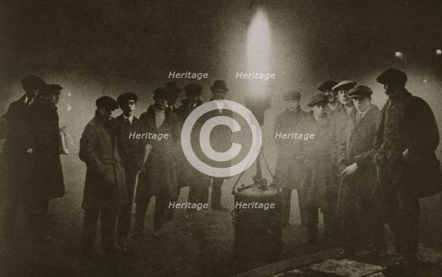 Gathering around an acetylene flare at a traffic control point in the fog, early 20th century. Artist: Unknown