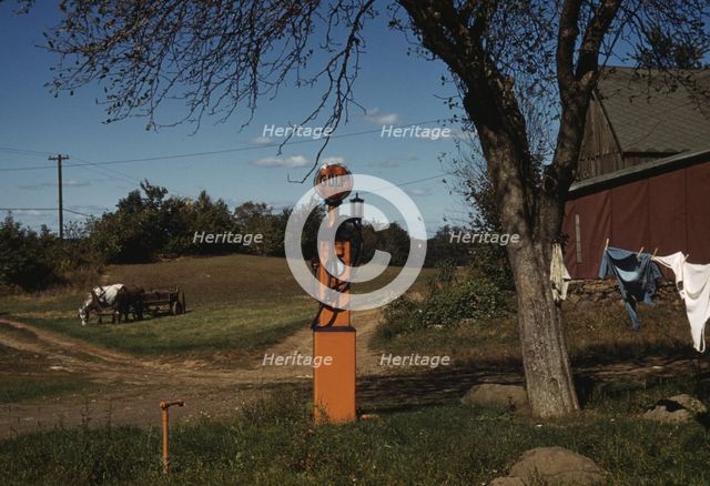 Gas pump with clothesline, barn and horse-drawn wagon in background, between 1941 and 1942. Creator: Unknown.